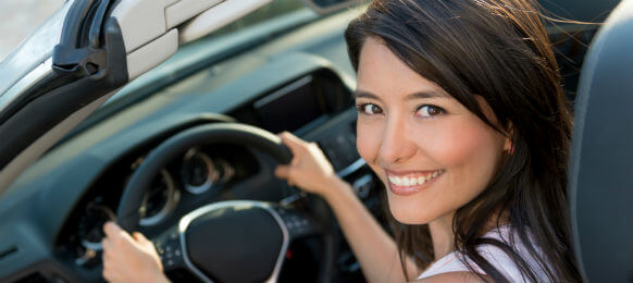 lady smiling to the camera while driving a convertible rental car