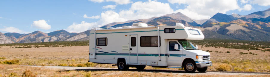 white campervan travelling on the road with scenic mountain backdrop