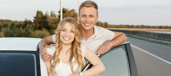 happy couple posing next to their white car