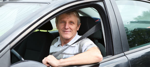 fastened smiling Caucasian senior man sitting in a car hire on driver seat