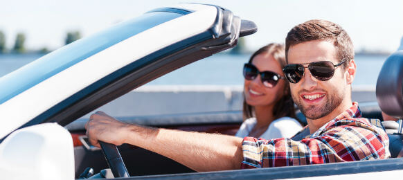 smiling traveling couple inside a rental car