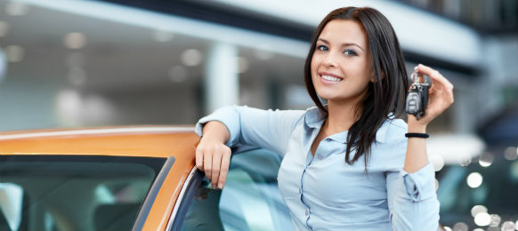 woman beside her orange car and showing her car key