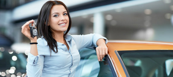 smiling female executive posing beside her new car