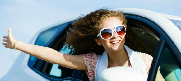 young pretty woman wearing sunglasses while driving in a car hire